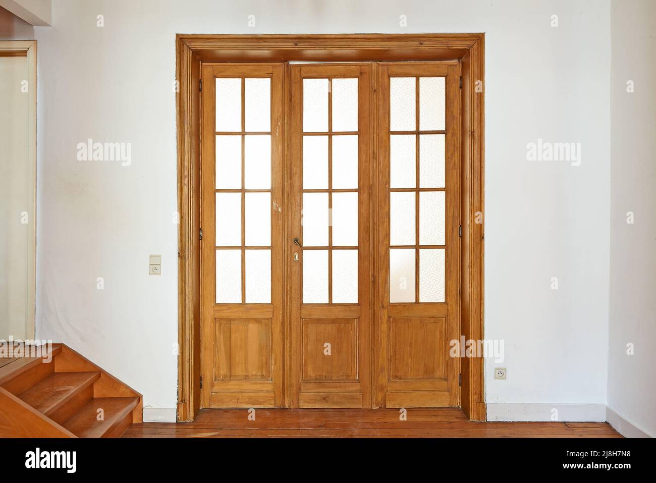 Porta interna in legno invecchiato con cornici in vetro in camera vuota Foto Stock