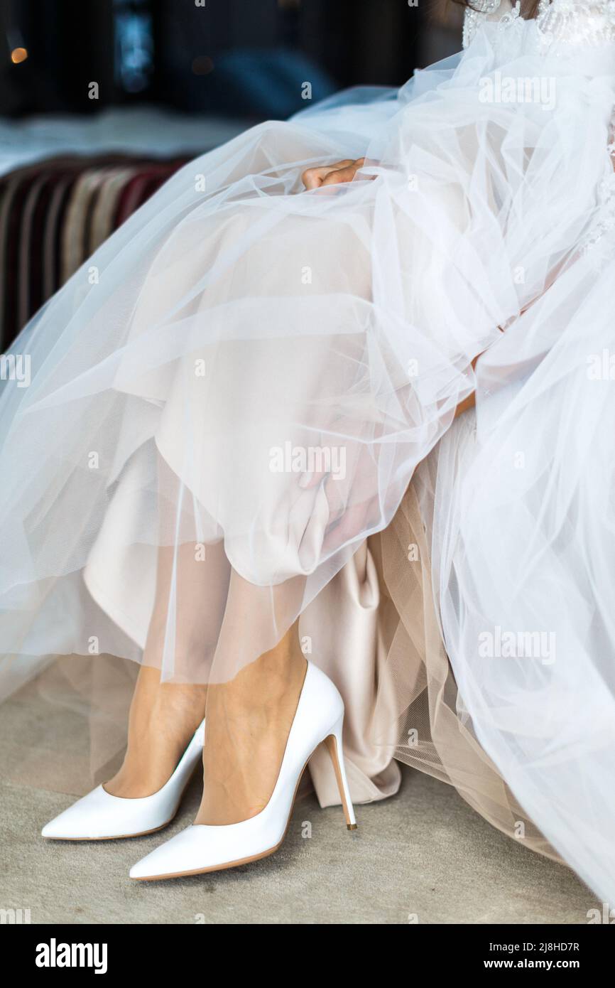 Sposa mettendo sul suo bianco scarpe matrimonio. Foto Stock