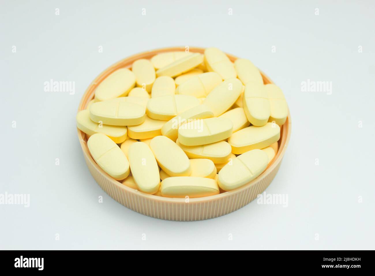 Una pila di compresse di supplemento di calcio e vitamina D isolate su sfondo bianco Foto Stock