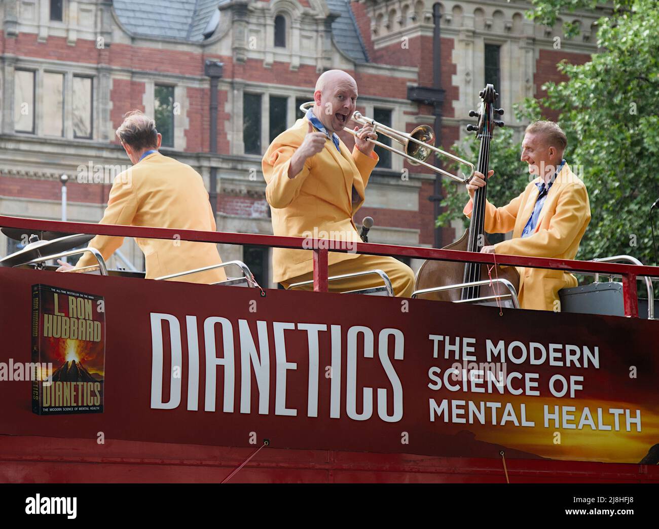 Membro di una Jazz Swing Band dare Un pollice in su sulla parte superiore di un Open Top Red London Bus Pubblicità Dianetics Salute mentale creato da L. Ron Hubbard Foto Stock