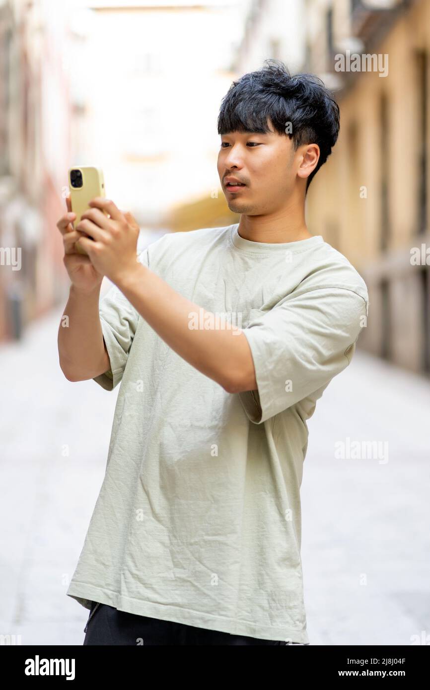 Asian che invia un messaggio dal suo nuovo smartphone Foto Stock