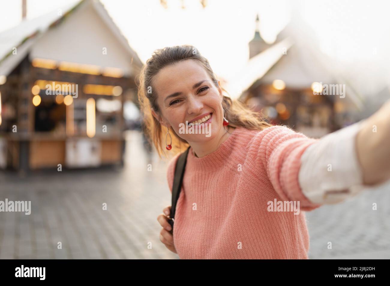 felice 40 anni donna alla fiera in città prendendo selfie. Foto Stock