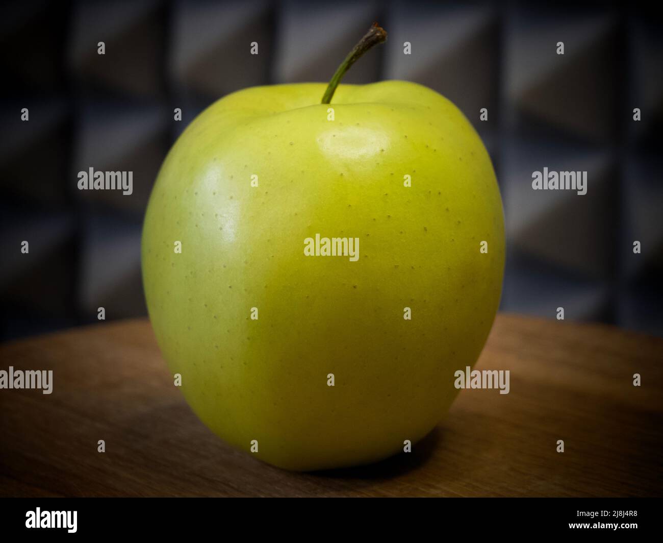 Golden Delicious è una mela gialla, una delle 15 cultivar più popolari negli Stati Uniti. Una mela singola su una superficie di legno, primo piano. Foto Stock