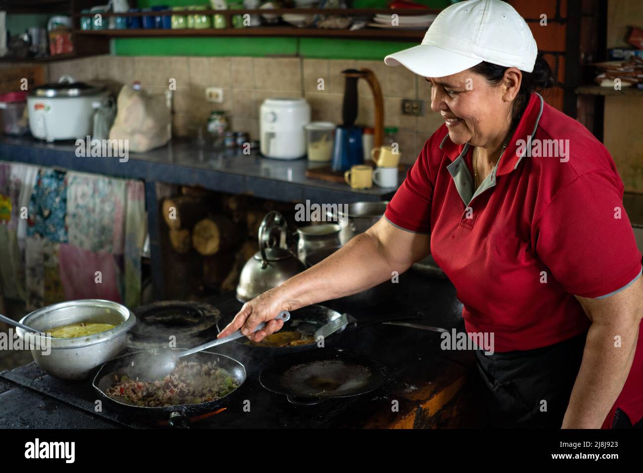 La donna sorride mentre cuoca la colazione tradizionale in Costa Rica. Foto Stock