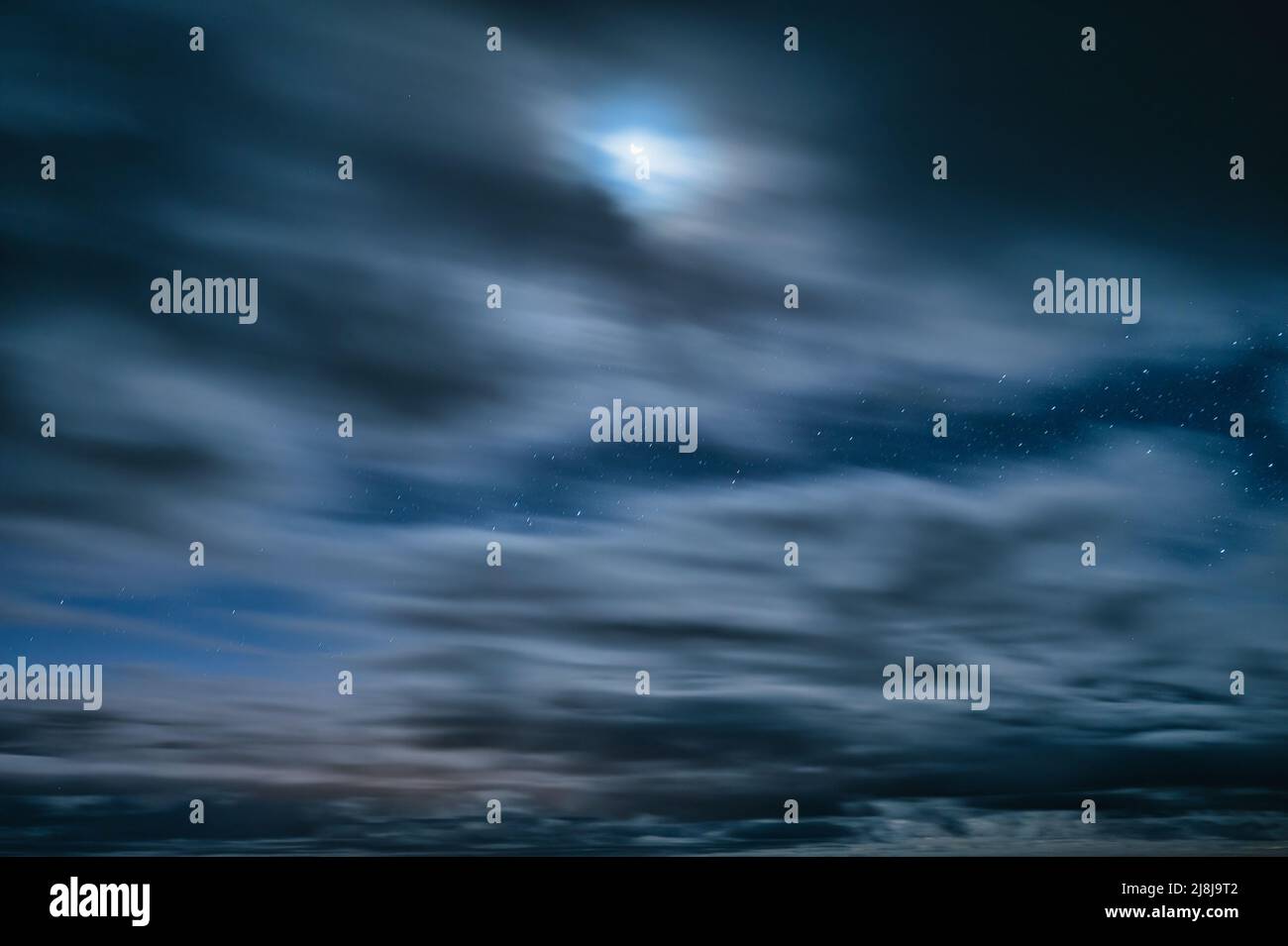 Lungo movimento di esposizione di nuvoloso che soffia attraverso il cielo blu con stelle e chiaro di luna di notte Foto Stock