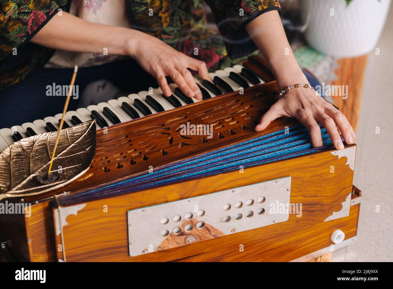 Mani di una donna seduta a terra e che suona l'armonio durante la pratica dello yoga kundalini. Foto Stock