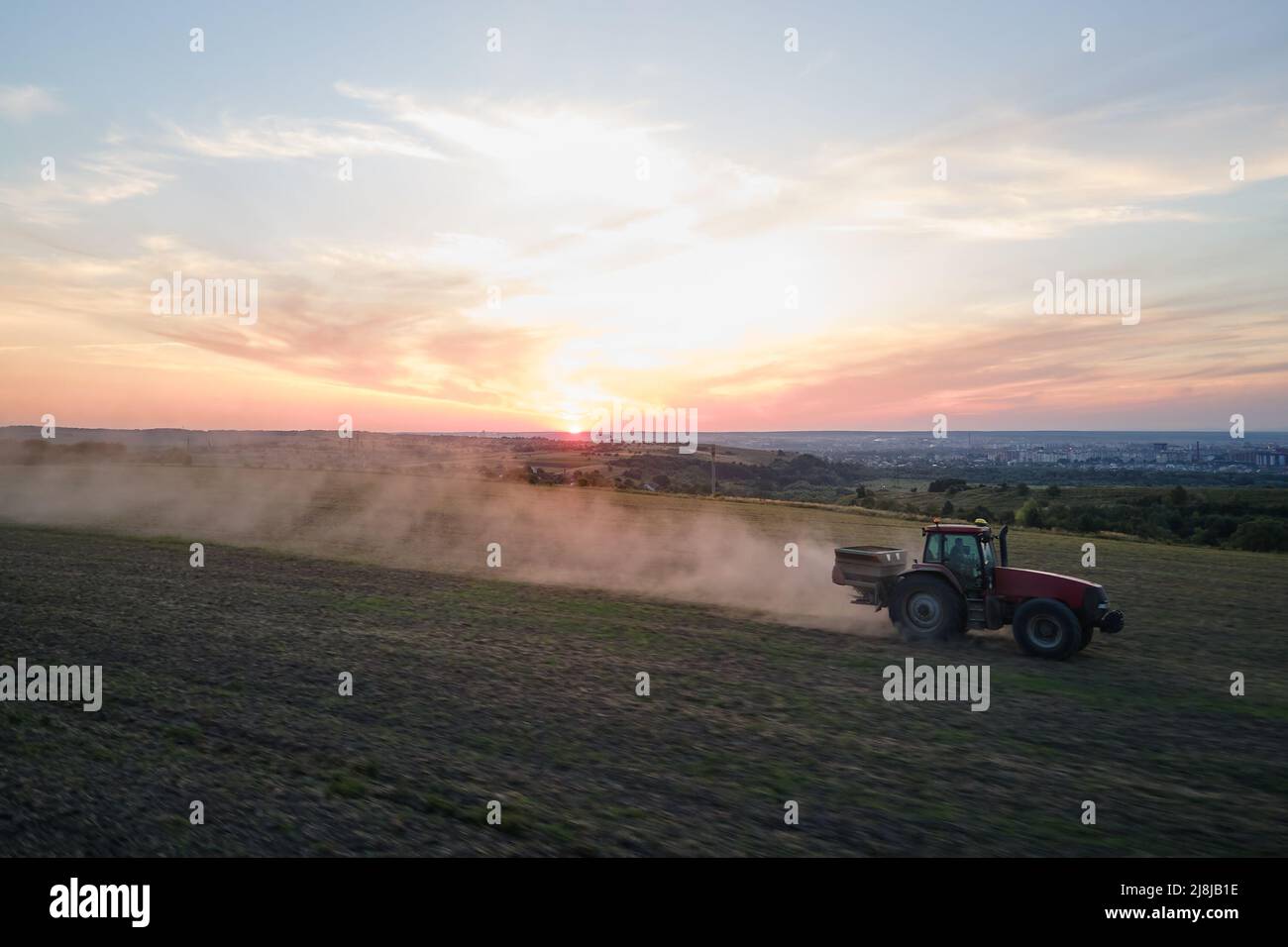 Trattore che irrorano fertilizzanti con prodotti chimici insetticidi erbicidi su campo agricolo al tramonto Foto Stock