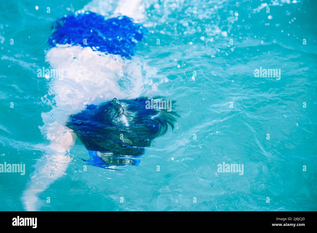 Top view Happy boy in blu nuotano nella piscina acqua calda e limpida Sunny estate giorno durante la vacanza. Vacanza in famiglia e concetto di turismo, s Foto Stock