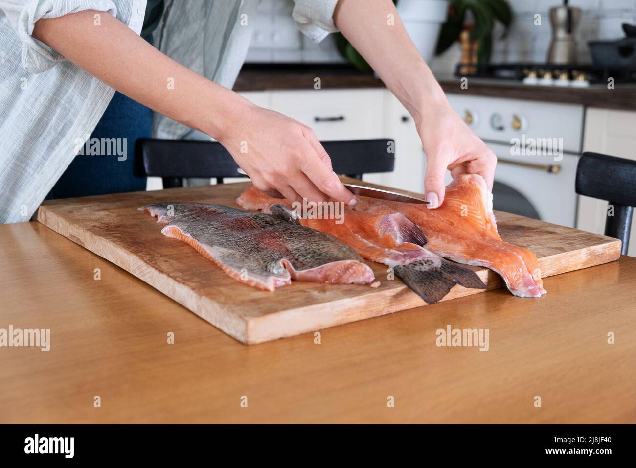 Le mani femminili tagliano il filetto di pesce rosso. Caviale rosso. Rimozione delle ossa di pesce. Carne di pesce rosso alla macelleria...concetto di cibo. Foto Stock