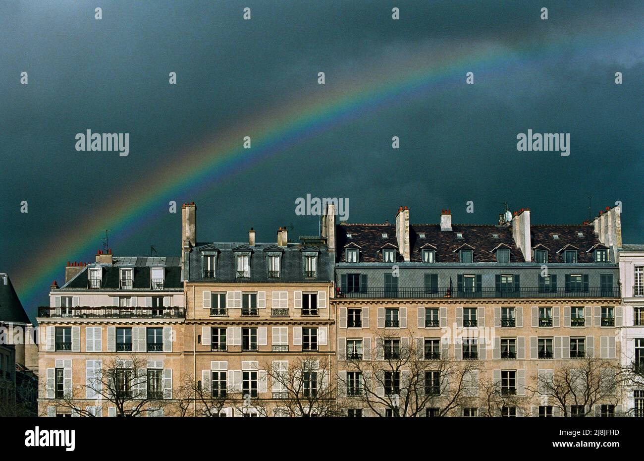 Un arcobaleno che galleggia sugli edifici lungo quai de Béthune su île Saint-Louis, visto da quai de la Tournelle sulla riva sinistra Foto Stock