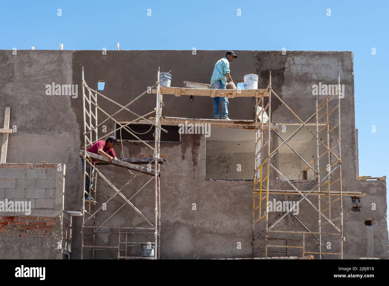 Gli operai edili su impalcature metalliche con tavole di legno applicano stucchi su un nuovo edificio, San Carlos, Sonora, Messico, Stati Uniti. Foto Stock