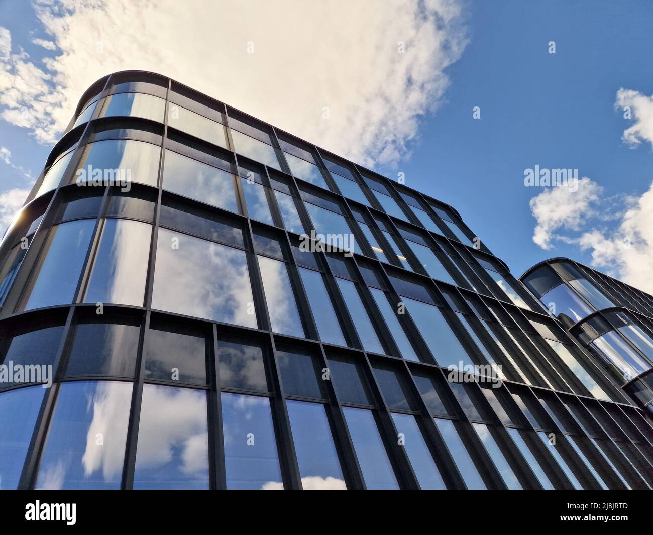 Architettura moderna e riflesso dal cielo nuvoloso blu. Il concetto di investimento immobiliare Foto Stock