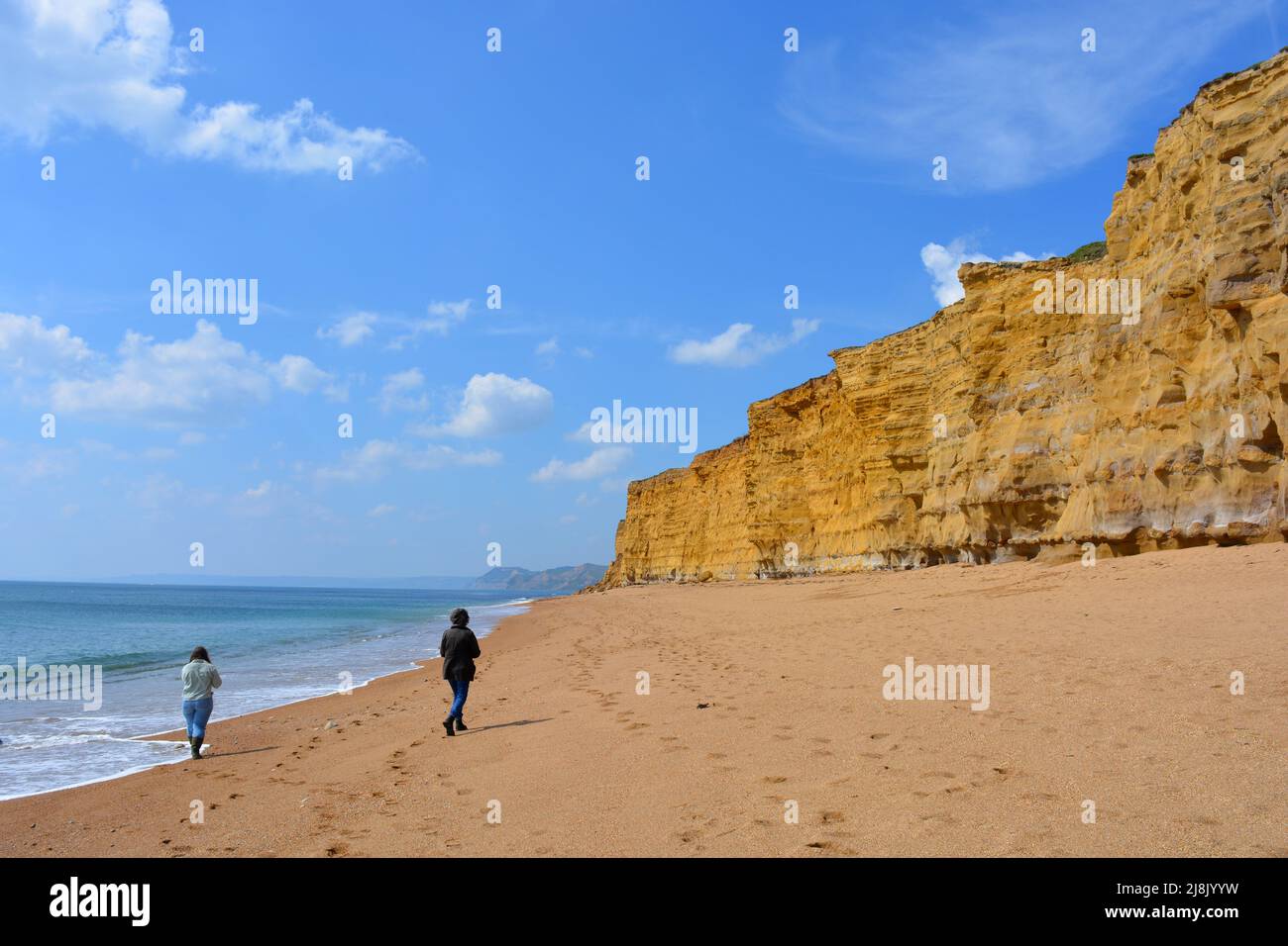 Due donne da dietro, camminando su Hive Beach, Burton Bradstock, parte del patrimonio mondiale bello Jurassic Coast in Dorset, Inghilterra Foto Stock