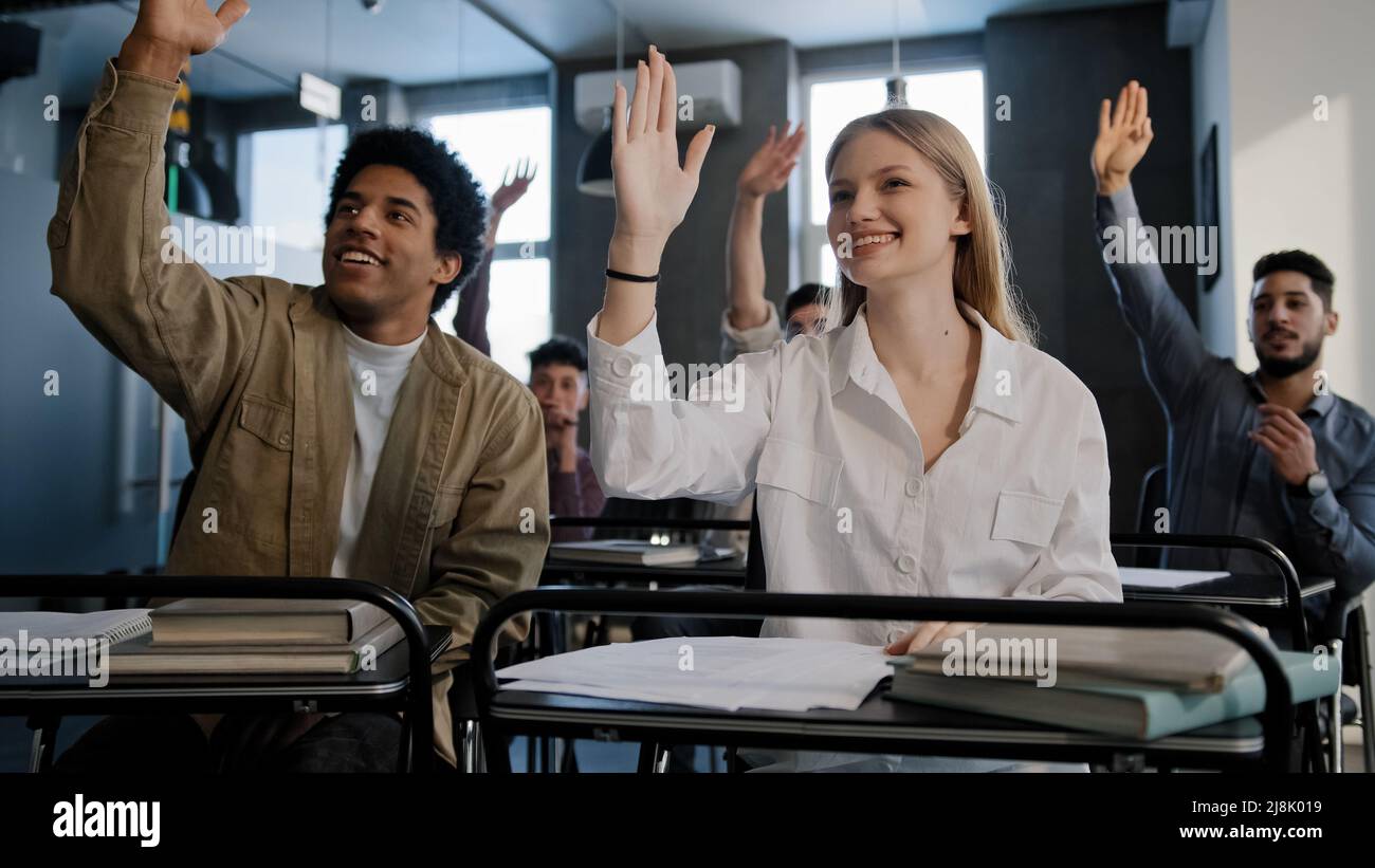 Diversi gruppi smart studenti seduti in aula a lezione ascoltando attentamente la lezione degli insegnanti che studiano a scuola o all'università tutti alzando le mani Foto Stock