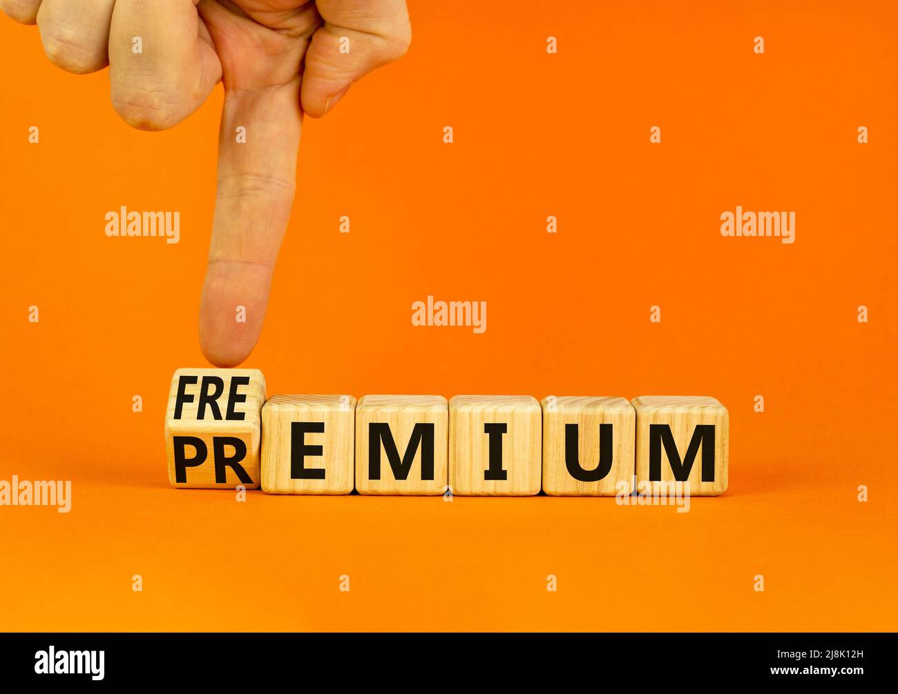 Simbolo Premium o freemium. L'uomo d'affari trasforma i cubi di legno e cambia la parola di concetto Premium in Freemium. Bella tabella arancione sfondo arancione. Foto Stock