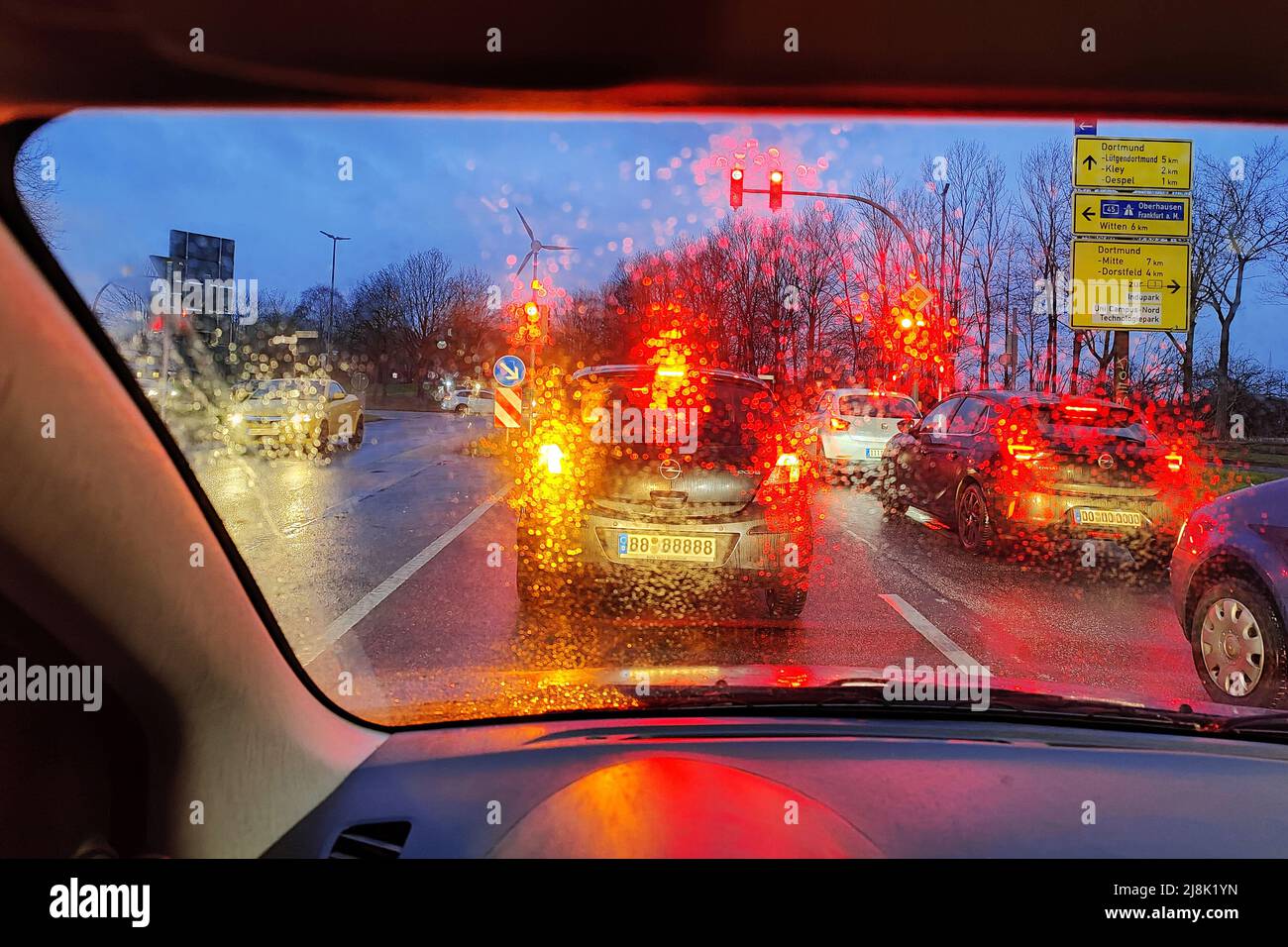 Vista attraverso una finestra bagnata con vista sfocata sul traffico in serata, Germania, Renania Settentrionale-Vestfalia Foto Stock