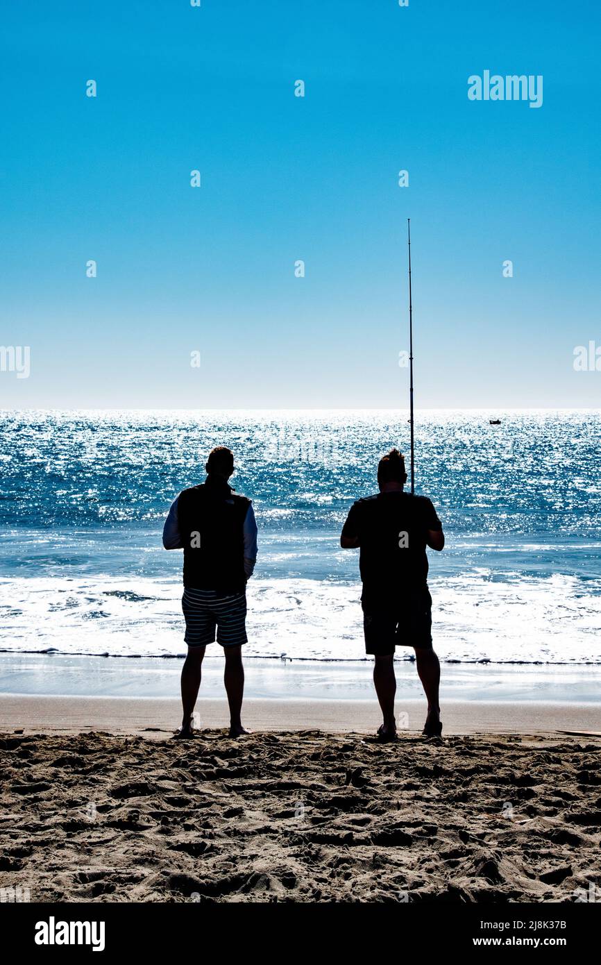 Due figure si affacciavano sull'Oceano Pacifico. Uno è la pesca, l'altro è bere. Preso lungo la costa di Bodega Bay, CA. Foto Stock