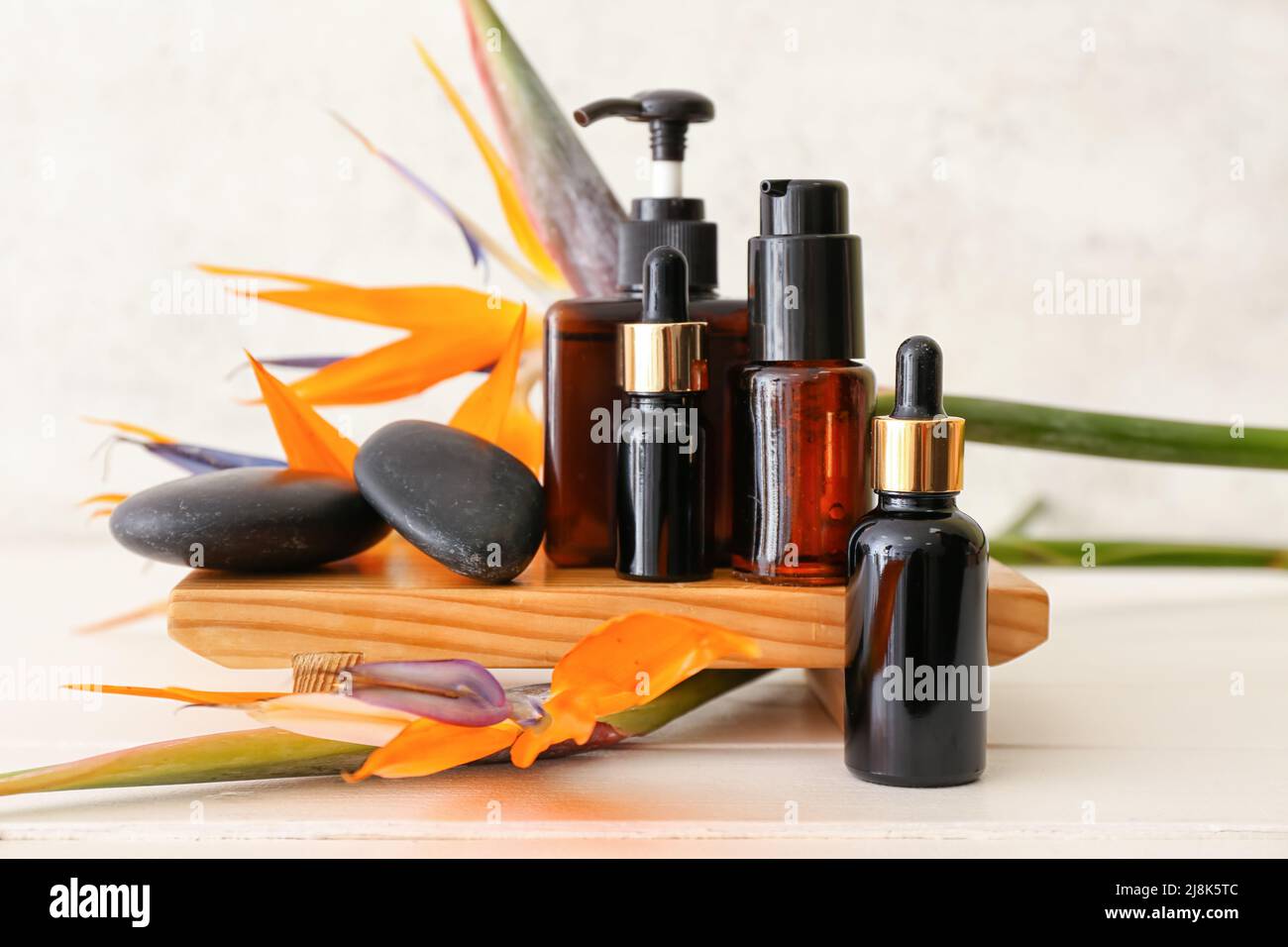 Composizione con diversi prodotti cosmetici e fiori di strelitzia su sfondo chiaro Foto Stock