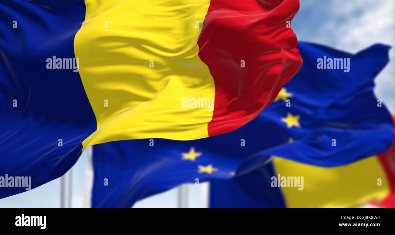 Dettaglio della bandiera nazionale della Romania che sventola nel vento con la bandiera dell'Unione europea sfocata sullo sfondo in una giornata chiara. Democrazia e politica. E Foto Stock