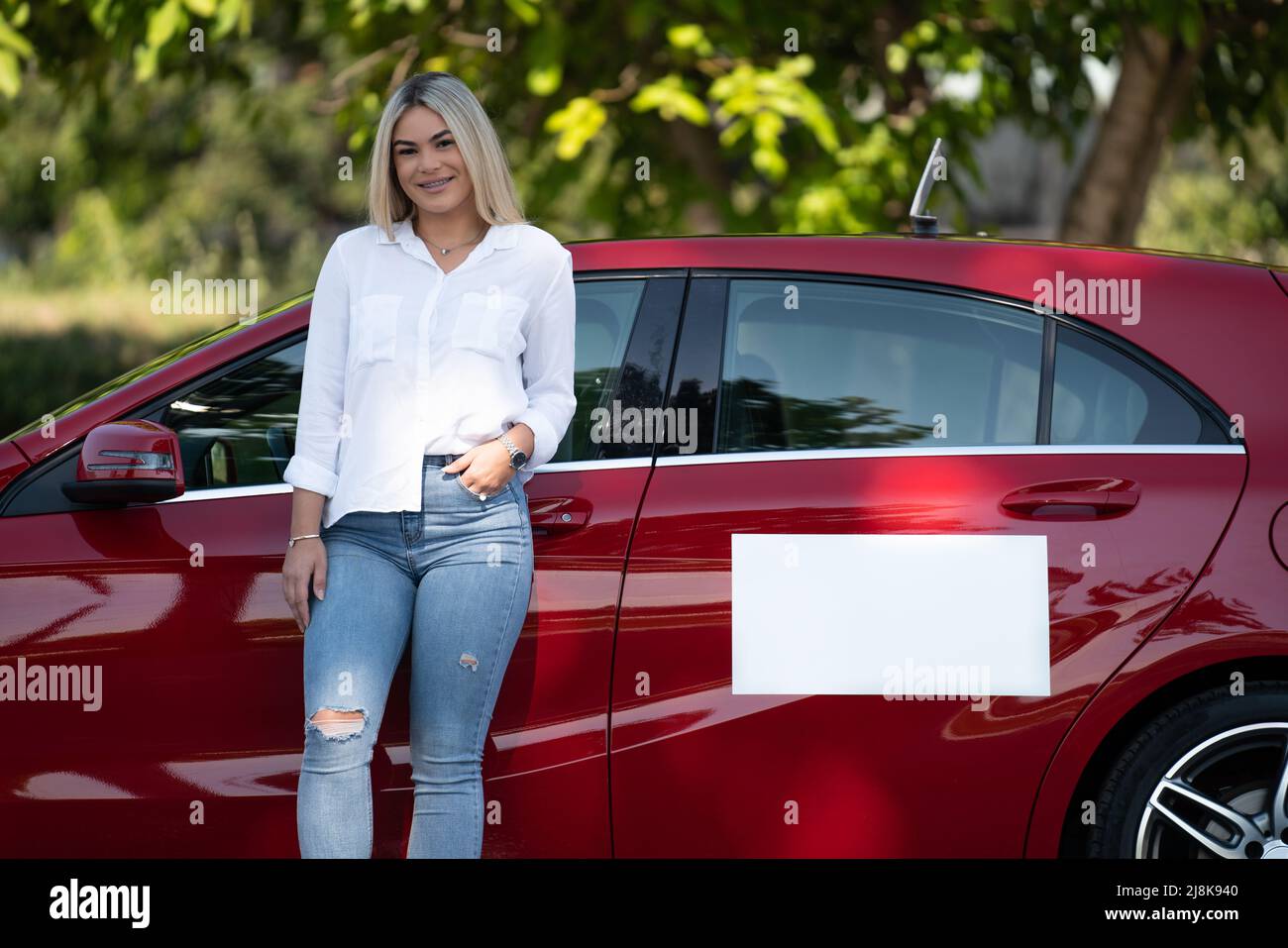 Happy Woman Instructor in prestito sulla sua auto - presumibilmente ha una pausa dalla guida Foto Stock