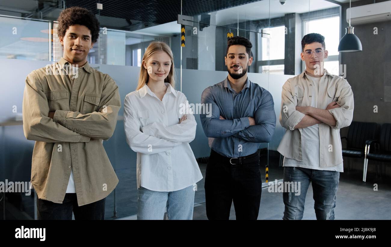 Felice orgoglioso gruppo professionale diversi uomini d'affari si levano in ufficio con le braccia incrociate sorriso guardando con fiducia fotocamera di successo Foto Stock