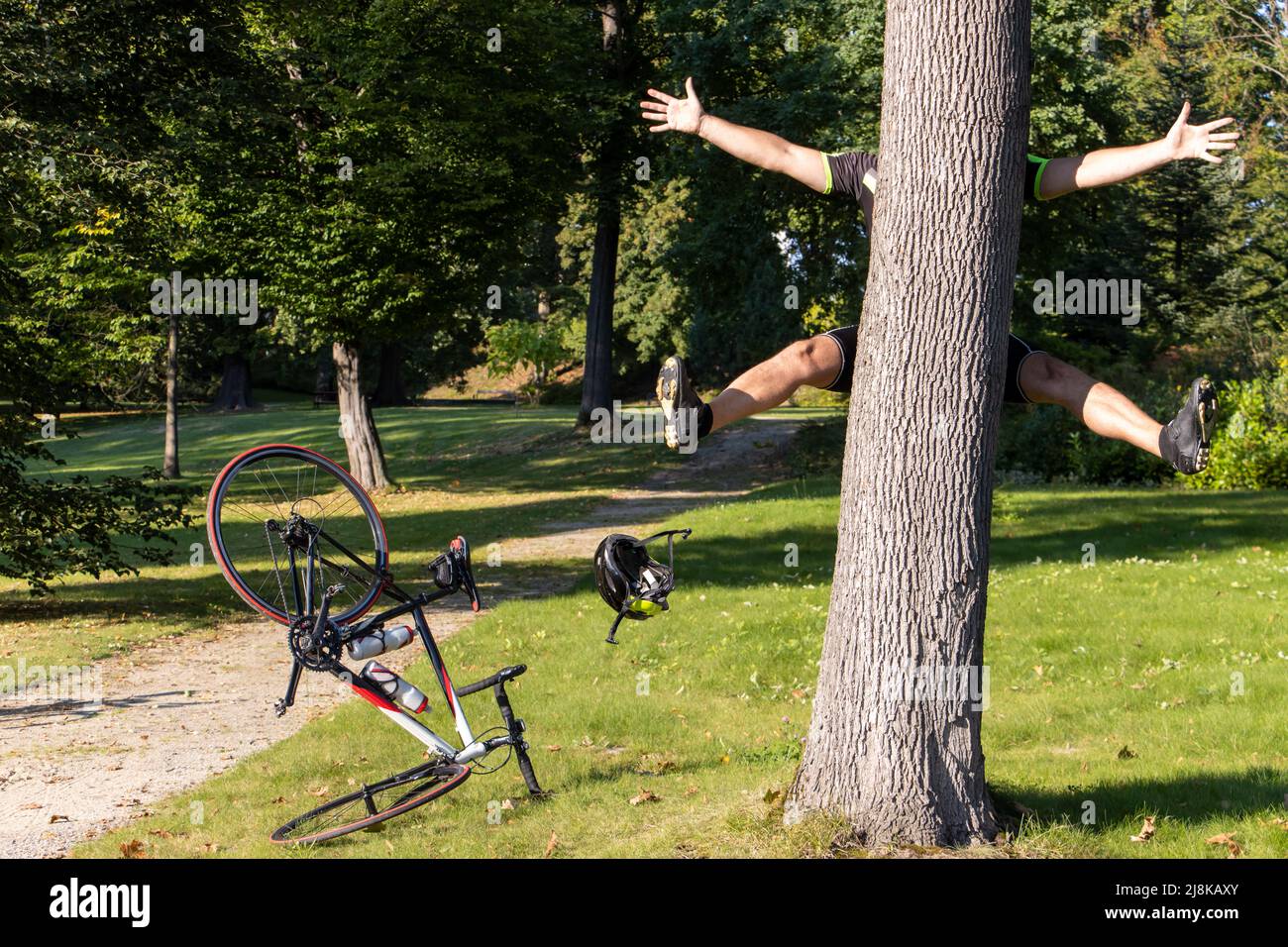 Un ciclista urta in un albero vicino ad un percorso in un parco. Foto Stock