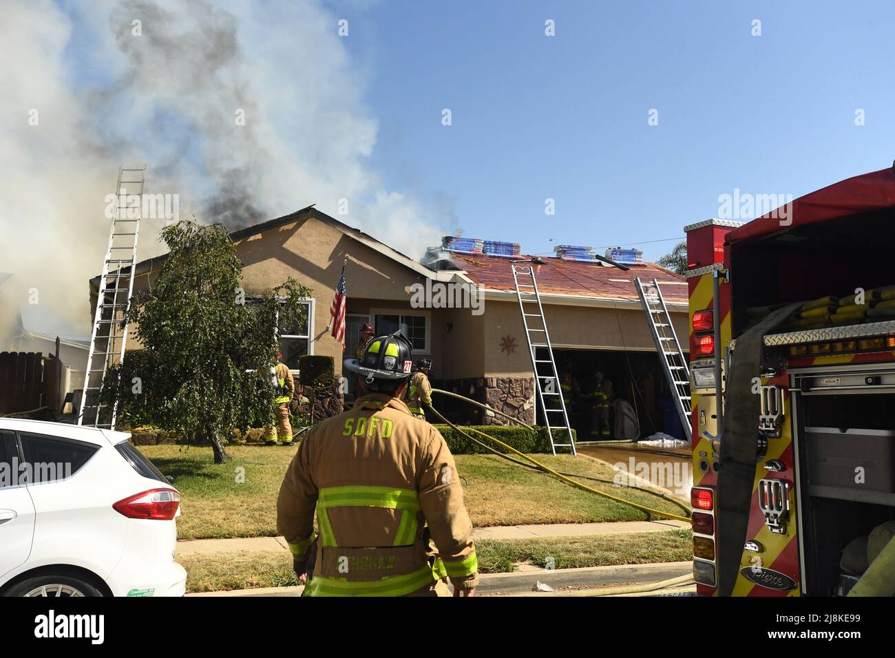 Un incendio nella casa nel quartiere di Kearny Mesa di San Diego ha portato ad una prima assegnazione di allarme dei vigili del fuoco di San Diego Fire-Rescue. Il fuoco in rapido movimento distrusse la parte vivente della casa, con solo il garage che sopravvisse alle fiamme. A seguito di un crollo completo del tetto sopra i quartieri viventi, i vigili del fuoco hanno dovuto usare una scala aerea per terminare estinguendo le fiamme. I due occupanti della casa sono fuggiti senza danni . La causa dell'incendio è stata determinata come recente lavoro sul tetto della struttura e i danni totali sono stati fissati a $400.000 USD. Foto Stock