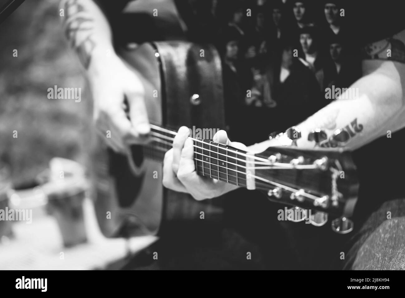Un uomo che suona una chitarra acustica. Immagine in bianco e nero. Vista frontale. Foto Stock