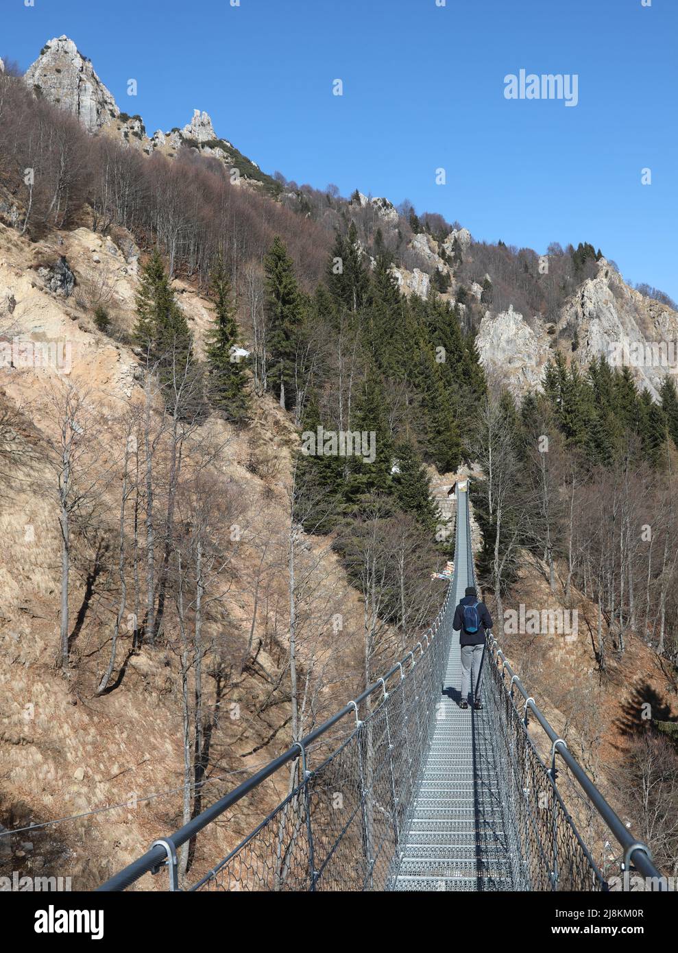 lungo ponte sospeso realizzato con funi d'acciaio e montagne sullo sfondo in inverno Foto Stock