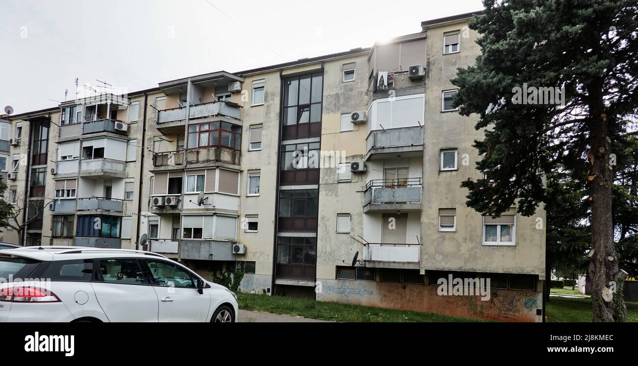 Umago, Croazia, 5 maggio 2022: Vecchio blocco di appartamenti di epoca socialista jugoslava con scala di vetro e balconcini Foto Stock