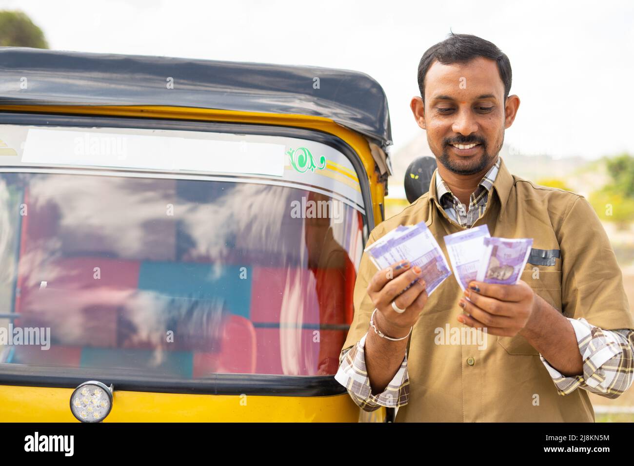 Felice sorridente auto Rickshaw conducente contare soldi mentre in piedi accanto a auto - concetto di successo business, finanziario, bancario e di lavoro autonomo Foto Stock
