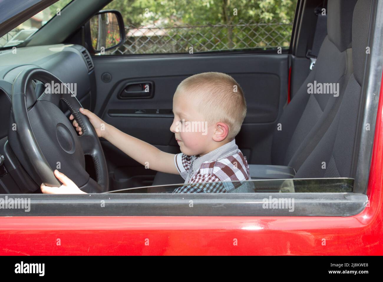 Little Boy giocando con un volante in un auto Foto Stock