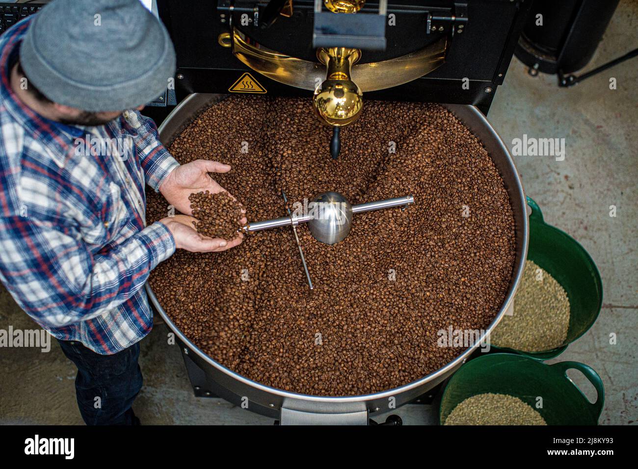 Uomo che tiene i chicchi di caffè torrefatti , la mano dell'uomo che tiene i chicchi di caffè dal torrefattore Foto Stock