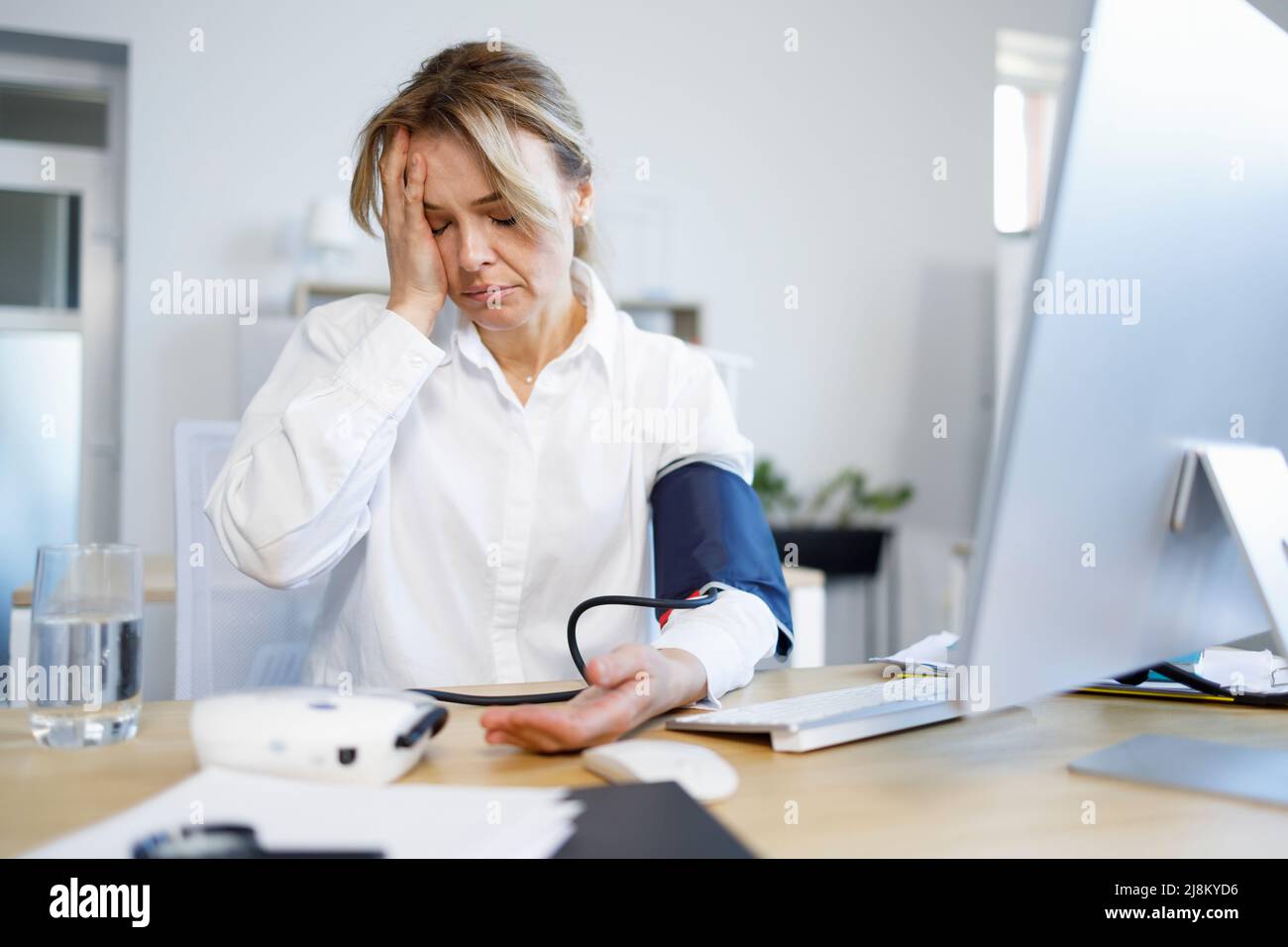 Donna d'affari con lavoro eccessivo che misura la pressione arteriosa con  un monitor per la pressione sanguigna Foto stock - Alamy