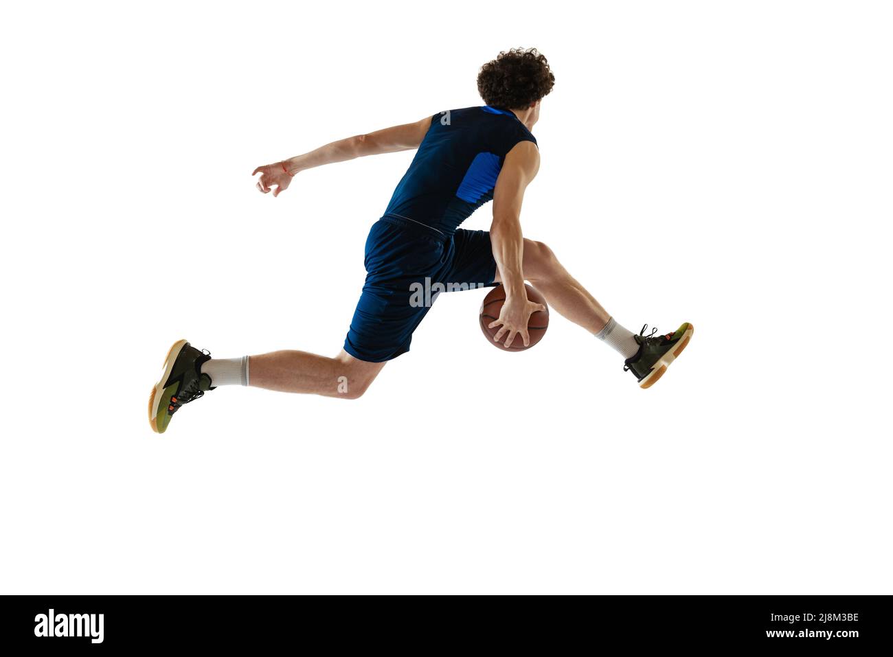 Ritratto dinamico del giovane uomo, giocatore di basket che gioca a basket isolato su sfondo bianco. Concetto di sport, movimento, energia e azione Foto Stock