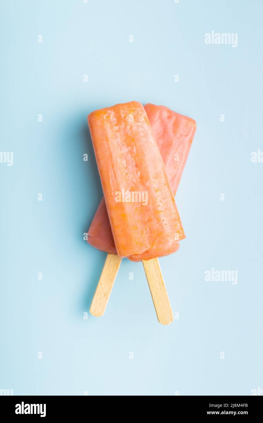 Ghiacciato fruttato. Dolce pop cicle su un tavolo blu. Vista dall'alto. Foto Stock