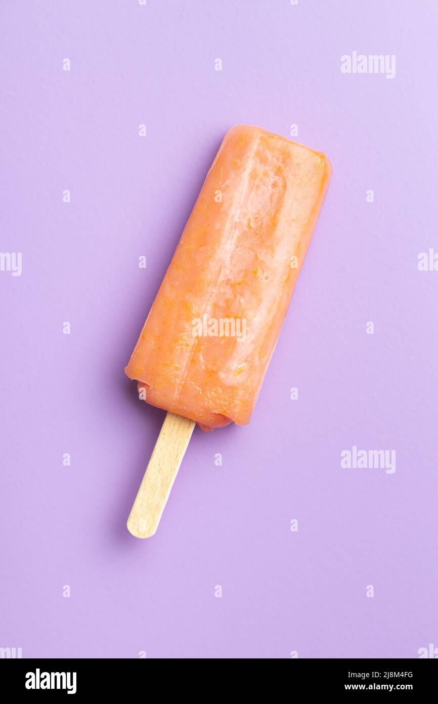 Ghiacciato fruttato. Dolce pop cicle su sfondo viola. Vista dall'alto. Foto Stock