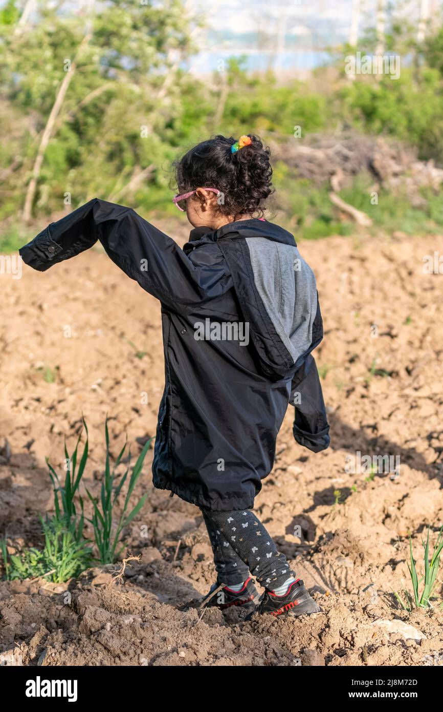 Fuoco selettivo sparato di ragazza in cappotto nero tra gli alberi. Foto Stock