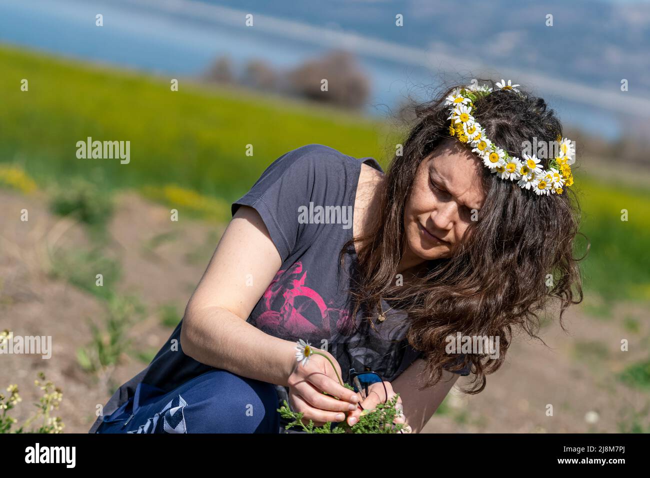 Fuoco selettivo girato da profilo opposto di donna con corona fatta di margherita sulla sua testa. Foto Stock