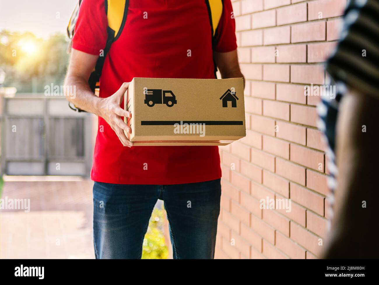 Primo piano dell'addetto alla consegna consegna consegna la scatola di cartone al cliente all'ingresso a casa Foto Stock