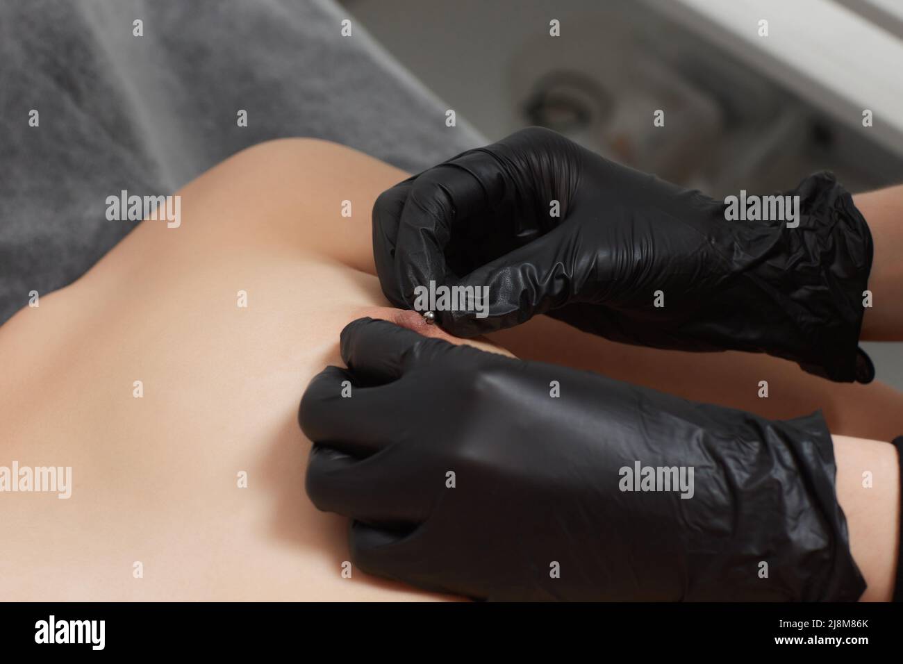 Procedura di piercing capezzolo per le donne primo piano di un seno nudo Foto Stock