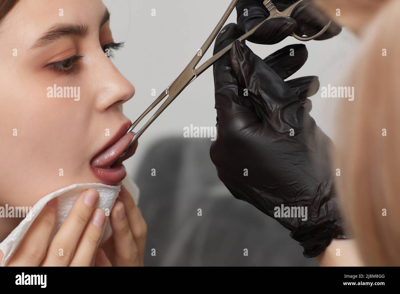 Operazione di piercing della linguetta professionale che tiene il gioiello Foto Stock