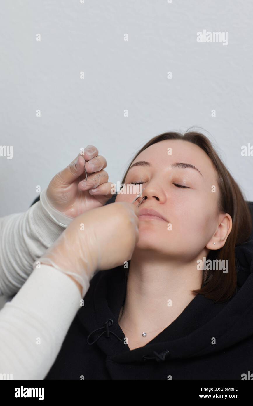 Primo piano del visage di una giovane donna con piercing appeso al naso Foto Stock