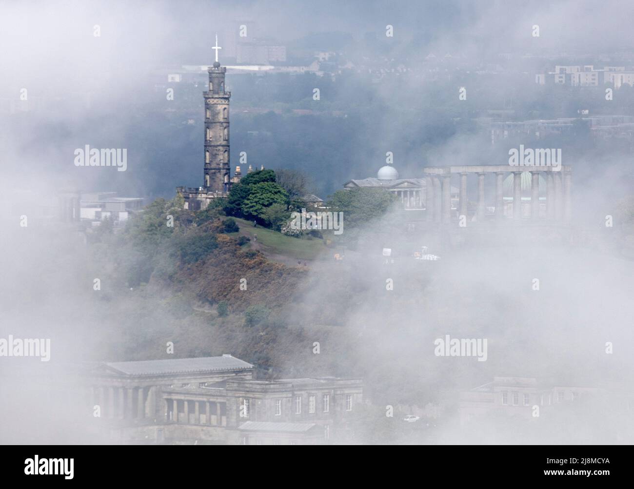 Edimburgo, Scozia, Regno Unito. 17th maggio 2022. Haar o fret di mare che si sposta sopra il centro della città, è una nebbia di mare fredda. Si verifica più spesso sulla costa orientale della Gran Bretagna tra aprile e settembre, quando l'aria calda passa sul freddo Mare del Nord. Nella foto: L'architettura di Calton Hill, il Monumento Nelson, il Monumento Nazionale, il centro dell'osservatorio e la vecchia scuola reale sotto avvolta nella nebbia atmosferica che ha cominciato a sollevarsi da 11am quando la temperatura è aumentata da 10 gradi a 12 gradi centigradi. Credit: Arch White/alamy Live news. Foto Stock