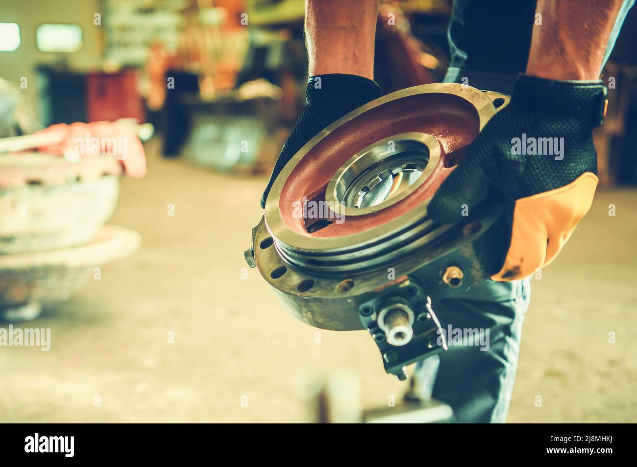 Meccanico di attrezzatura pesante con una parte di ricambio nelle sue mani primo piano. Riparazione di macchine per l'industria edile. Foto Stock