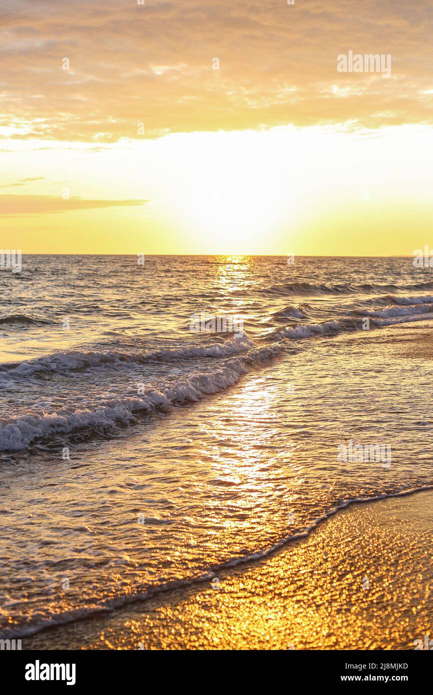 Le onde di mare sulla riva del mare si riversarano sulla sabbia in serata al tramonto Foto Stock