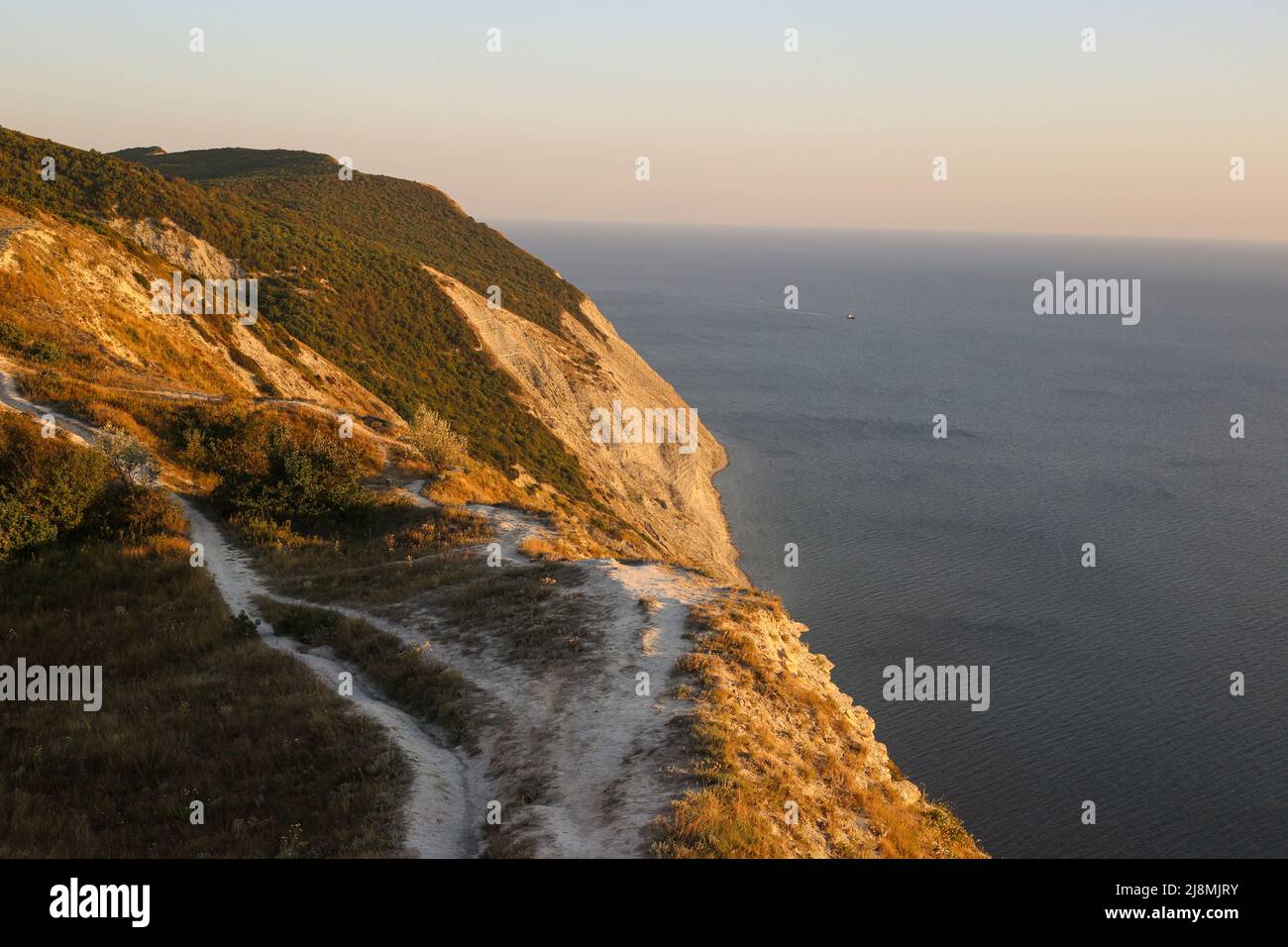 Montagne rocciose con vegetazione isola paesaggio per i turisti lungo il mare al tramonto che domina l'orizzonte Foto Stock