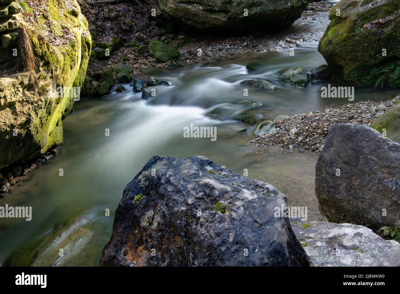 acqua sfocata che scorre tra rocce grandi Foto Stock