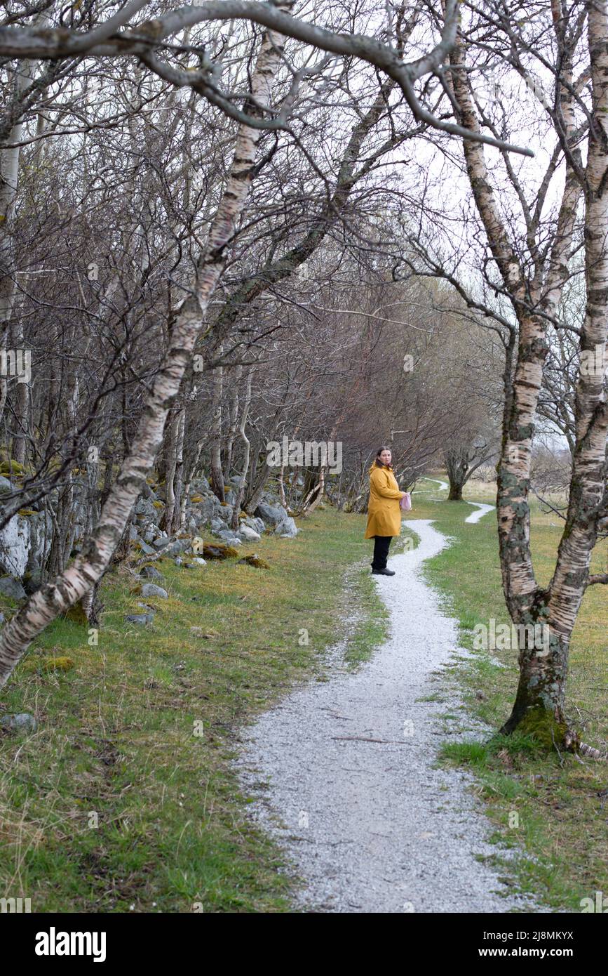 Una donna in piedi su un sentiero tortuoso, che guarda confusa e insicura. Illustra le malattie mentali e l'ansia. Foto Stock