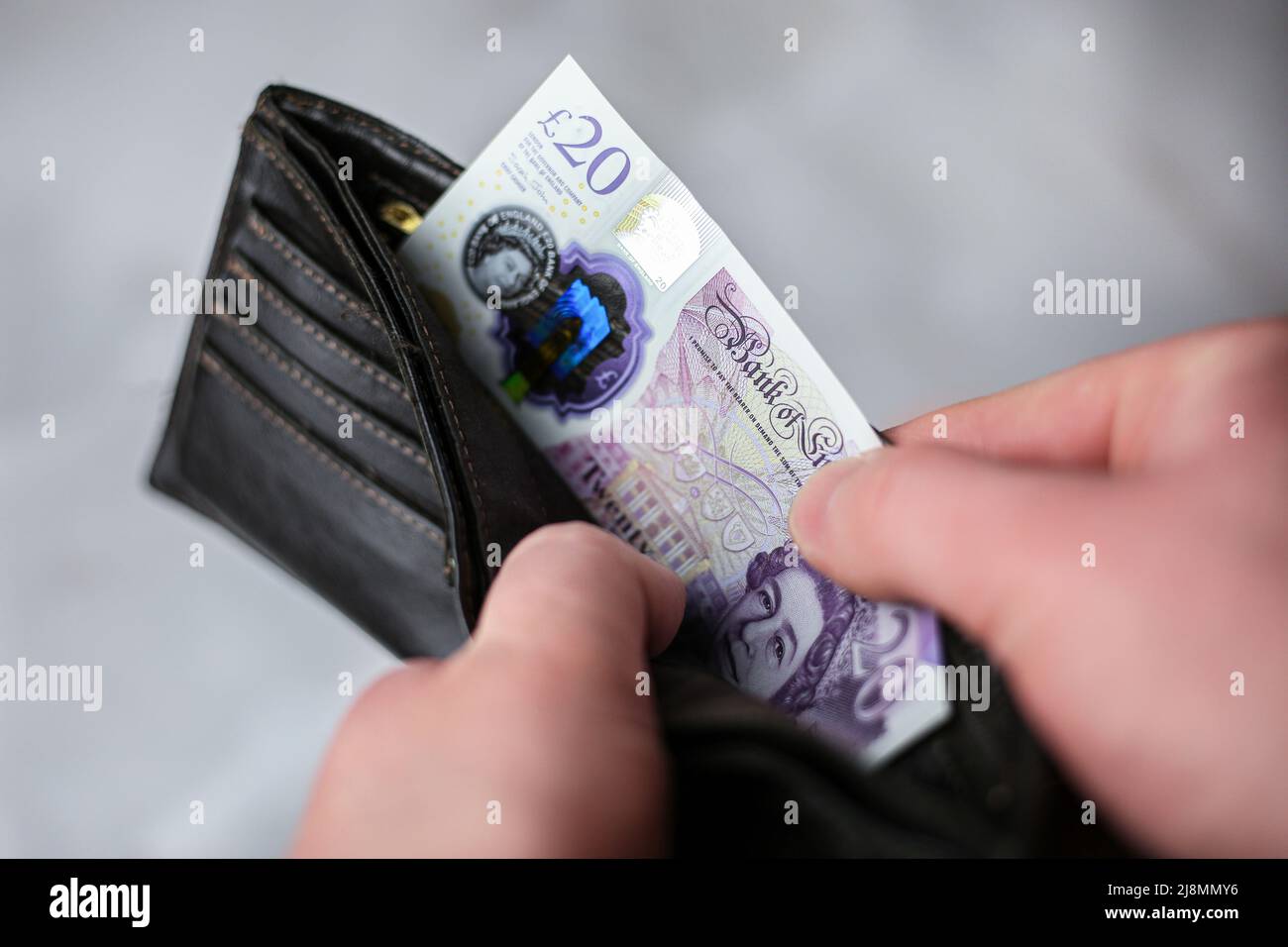 Mette in portafoglio o tira fuori 20 sterline inglesi fattura Foto Stock